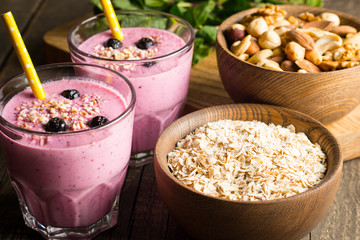 Glasses of berry smoothie with nuts, mint, blueberry, raspberry, and yogurt on wooden table. Weight loss and diet concept. 