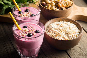 Glasses of berry smoothie with nuts, mint, blueberry, raspberry, and yogurt on wooden table. Weight loss and diet concept. 