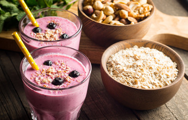 Glasses of berry smoothie with nuts, mint, blueberry, raspberry, and yogurt on wooden table. Weight loss and diet concept. 