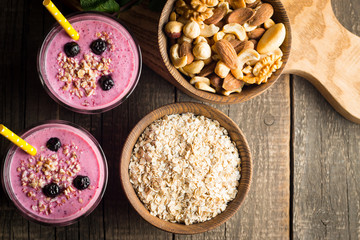 Glasses of berry smoothie with nuts, mint, blueberry, raspberry, and yogurt on wooden table. Weight loss and diet concept. 