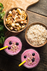 Glasses of berry smoothie with nuts, mint, blueberry, raspberry, and yogurt on wooden table. Weight loss and diet concept. 