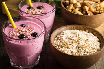 Glasses of berry smoothie with nuts, mint, blueberry, raspberry, and yogurt on wooden table. Weight loss and diet concept. 