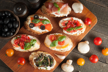 Italian tomato and cheese bruschetta. Tapas, antipasti with chopped vegetables, herbs and oil on grilled ciabatta and baguette bread.