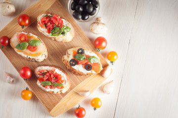 Italian tomato and cheese bruschetta. Tapas, antipasti with chopped vegetables, herbs and oil on grilled ciabatta and baguette bread.
