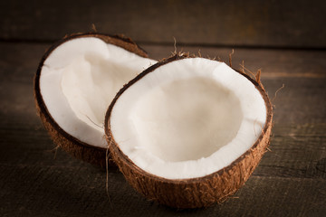 Ripe half cut coconut on a wooden background. Coconut cream and oil.