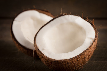 Fototapeta na wymiar Ripe half cut coconut on a wooden background. Coconut cream and oil.