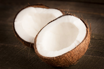 Ripe half cut coconut on a wooden background. Coconut cream and oil.