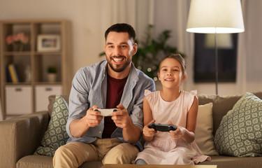 family, gaming and entertainment concept - happy father and little daughter with gamepads playing...