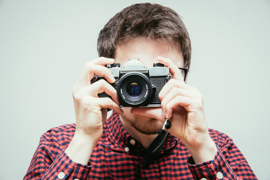 Young man is taking a picture with a vintage camera