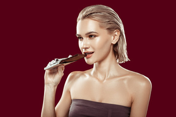Naklejka premium Young model working for food magazine biting piece of chocolate