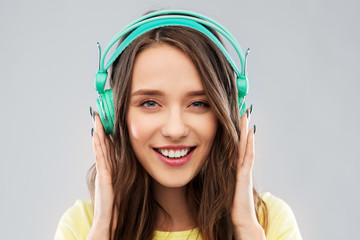 music, technology and people concept - happy young woman or teenage girl with headphones over grey...