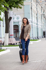 pretty adult woman with a suitcase walking on the apron landside