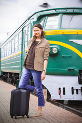 beautiful middle-aged woman with luggage on a railway platform near an old train