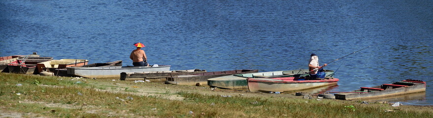 Two fishermen sitting on the boats fishing with protection from sun like umbrella