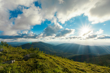 summer mountain scenery at sunset. stones on the grassy meadow. distant ridge beneath a cloudy sky....