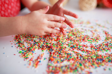 Obraz na płótnie Canvas Baby hands in sugar topping. Baby drawing. Baby fingers with candies. Easter sugar topping.