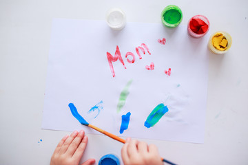 Baby drawing picture for mother's day with paints. Child draws with fingers. Baby draws with brush.