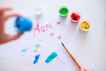 Baby drawing picture for mother's day with paints. Child draws with fingers. Baby draws with brush.