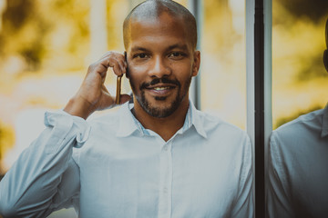 Confident african american male using smartphone outdoor. Office skyscrapers in the background
