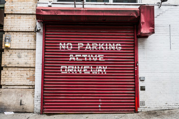 famous Manhattan red garage door with white inscription " No Parking active driveway" to keep the area clear. 