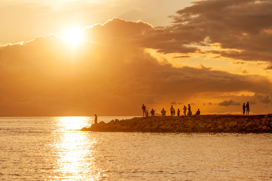 Tourists and fishermen watching amazing sunset from the pier of Mandre village on Pag island, Croatia