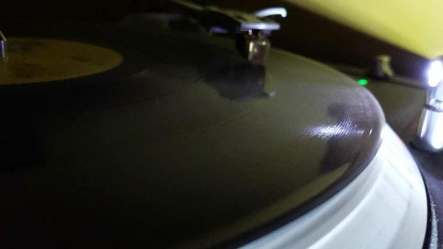 Closeup of a turntable spinning a record LP, with the LED reflecting the spinning grooves.