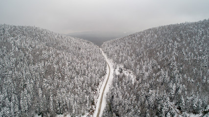 Aerial view of a road in idyllic winter landscape. Country road going through the beautiful snow covered landscapes.