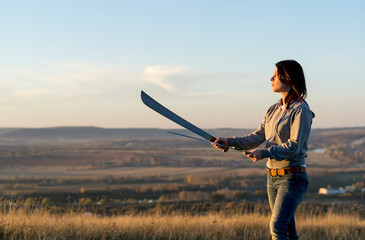Girl on a high mountain trains with a machete in the evening at sunset