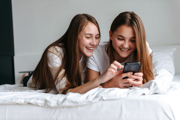 Two cheerful young teenage girls using mobile phone