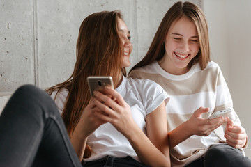 Two lovely young teenage girls using mobile phones
