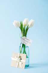 post card and bouquet of white tulips with happy mothers day greeting label on blue background