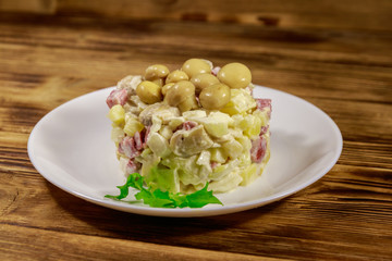 Potato salad with marinated mushrooms, sausage, onion and mayonnaise on wooden table
