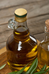 wooden tray with olive oil bottles and olive tree leaves on wooden surface