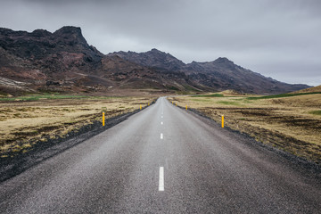 Obraz premium Straight forward asphalt road among rocky volcanic landscape of Reykjanes Peninsula in Iceland on a cloudy summer day