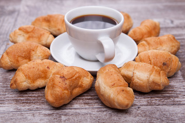 Freshly baked croissants on rustic wooden table with cup of coffee