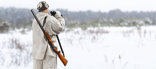 hunter with binoculars is in the winter field