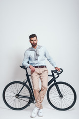 Fototapeta na wymiar Enjoying urban lifestyle. Full length of stylish young man leaning on his bicycle. Urban style