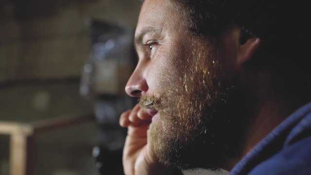 a man with a beard and mustache straightens his mustache and smiles