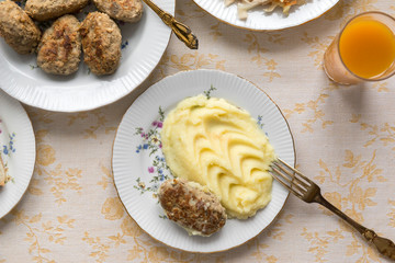 plate with the meat cutlet and mashed potatoes, a fork, a laid table, glass of juice