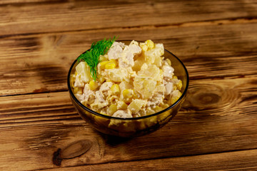 Festive salad with chicken breast, sweet corn, canned pineapple, cheese and mayonnaise on wooden table