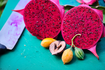 Pink dragonfruit cut open on chopping board with nut