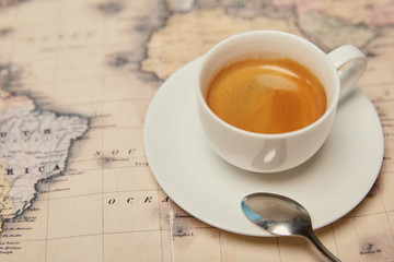 Selective focus of world map and coffee cup with spoon on saucer