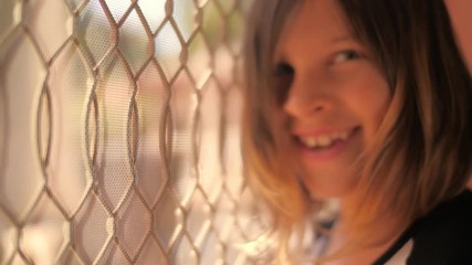 Cute happy 8 year old girl child turning head, looking at camera and laughing near door to sunny patio. Closeup, slow motion, 4K UHD.