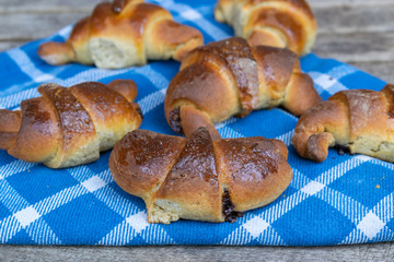 Tasty and fresh homemade croissants on a wooden background with a blue cloth.