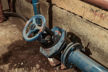 Blue pipe with a valve in the old basement