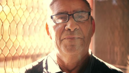 Confident healthy senior man looking at camera, backlit by beautiful sunlight. Slow motion, 4K UHD.