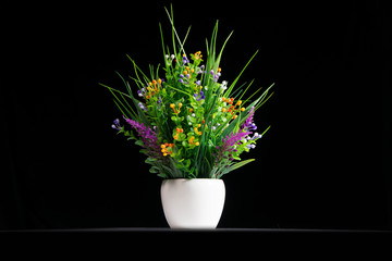 Beautiful artificial potted flowers on black background.