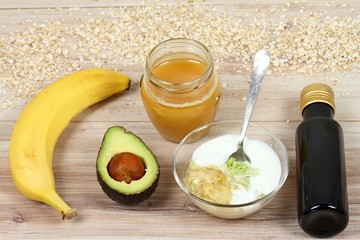 Ingredients for easy homemade facial mask. Banana, avocado, honey, olive oil, oatmeal and soured cream good for face mask, wood board