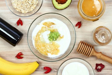 Ingredients for easy homemade facial mask. Banana, avocado, honey, olive oil, oatmeal and soured cream good for face mask, wood board