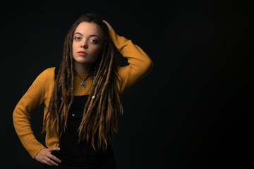 Portrait of a young girl with dreads on black background. Studio shoot.